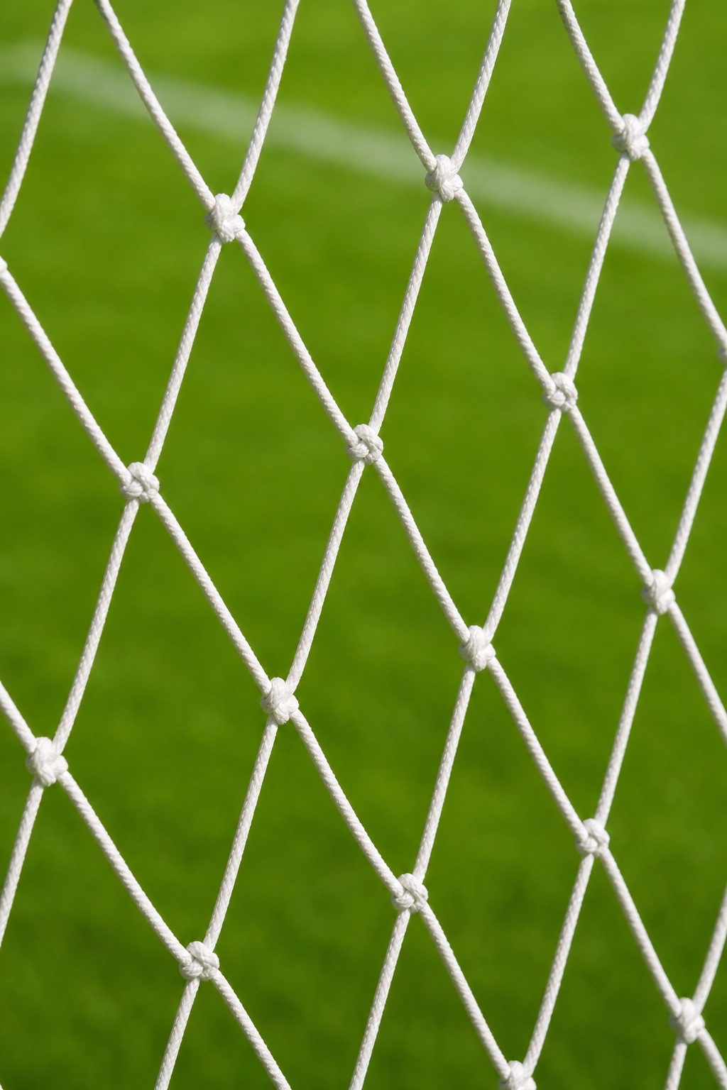 White soccer net over bright green turf with a close-up sports texture