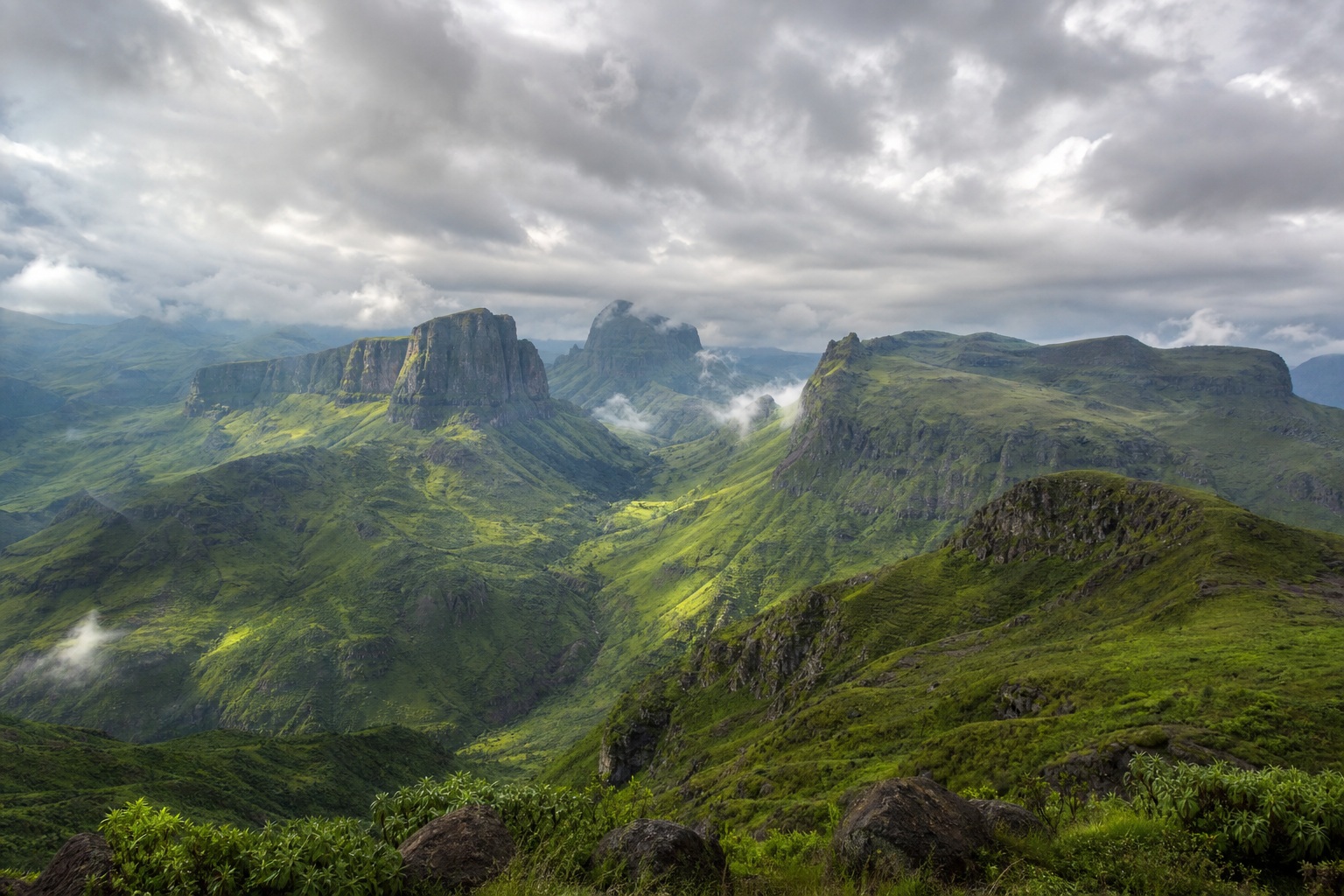 Lush green volcanic highlands under a soft overcast sky with dramatic peaks.