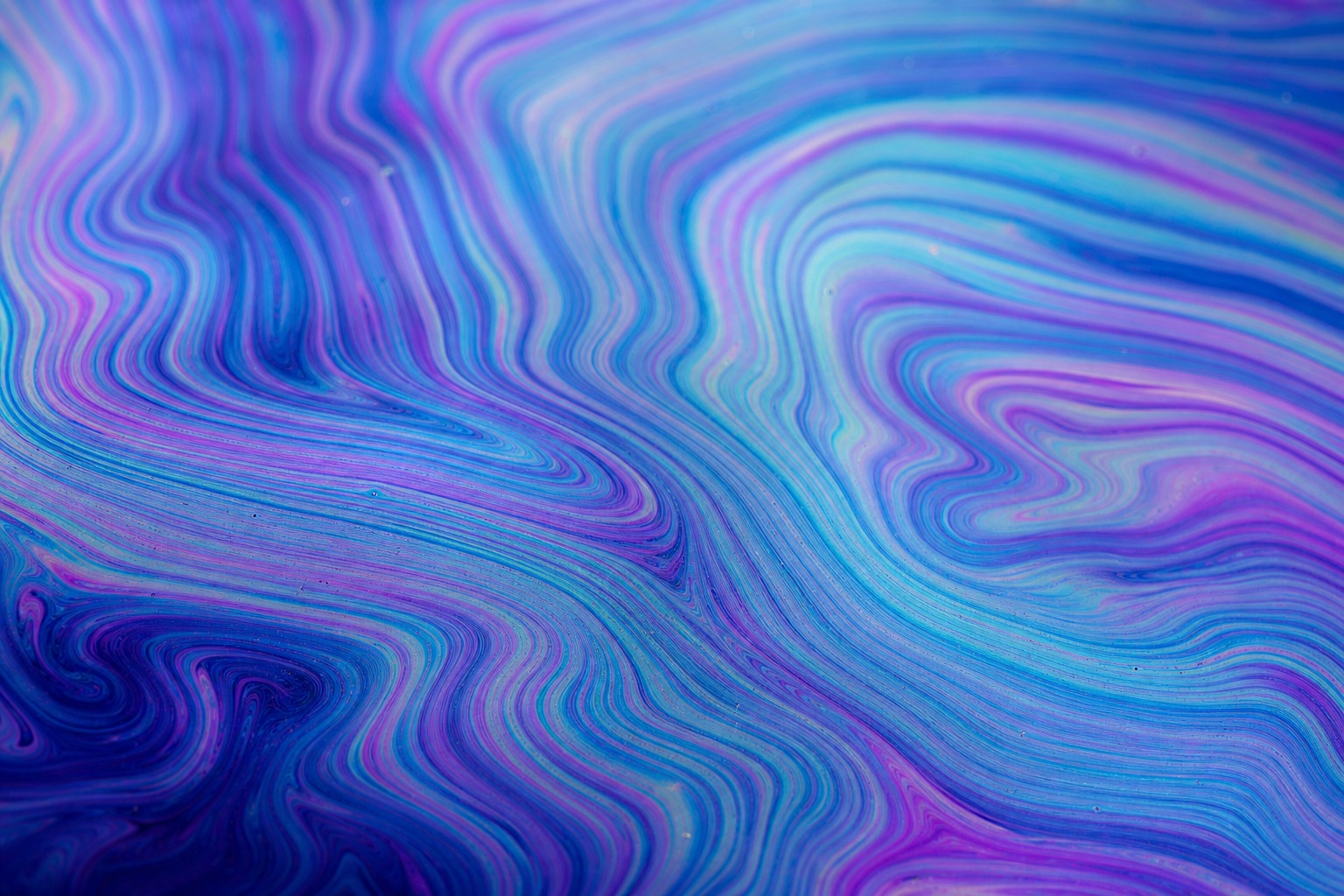 Cyan and magenta iridescent waves forming concentric interference rings.