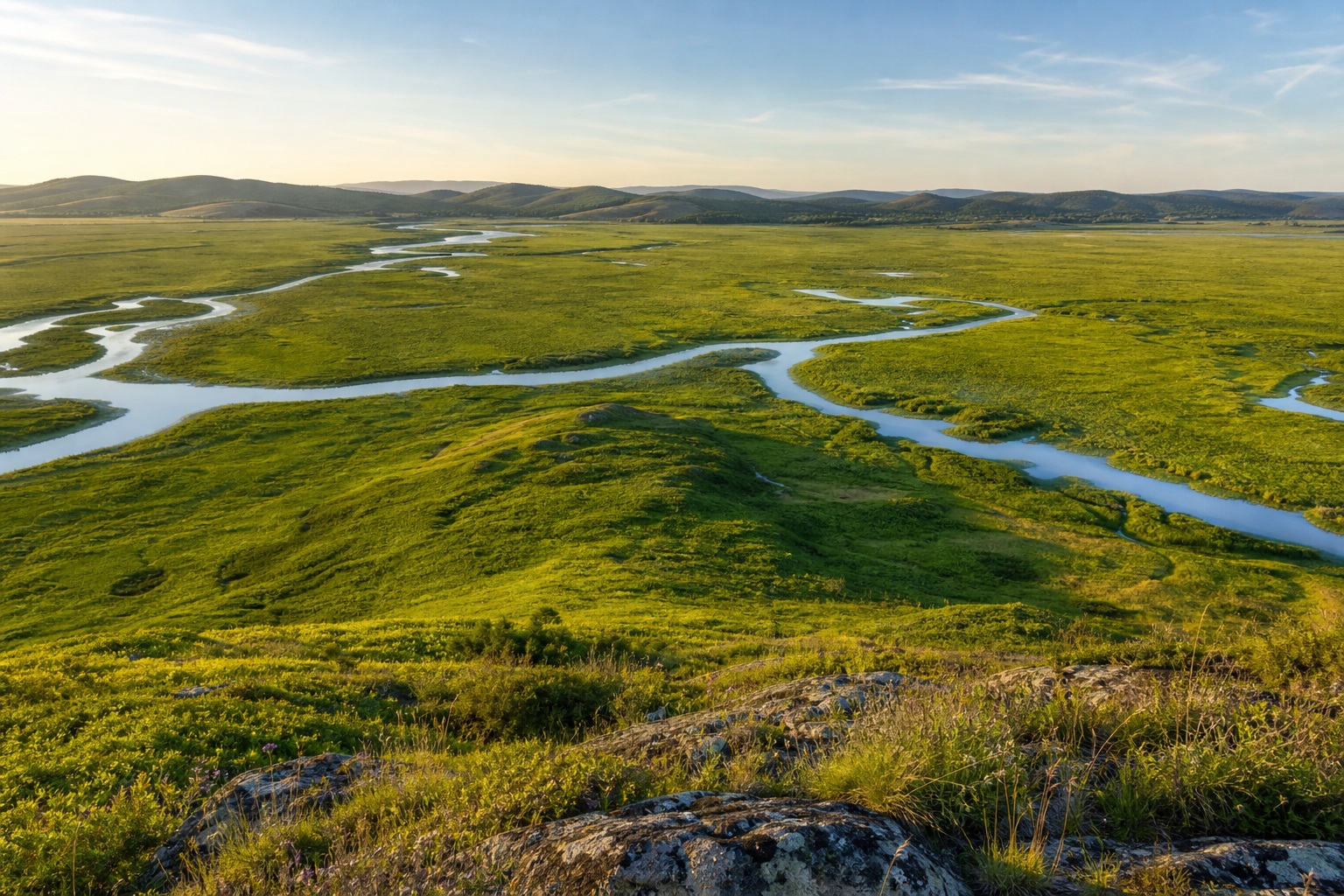 Rolling green farmland with winding water channels under a wide sky