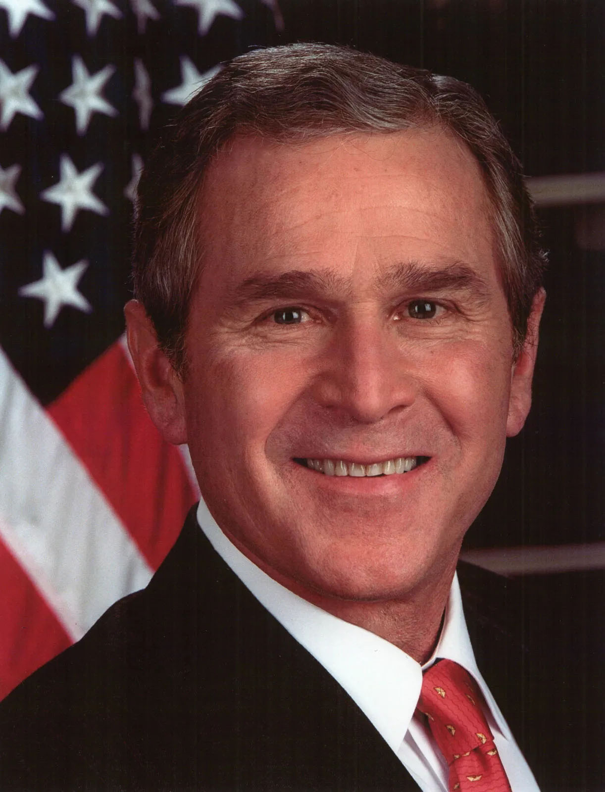 Official portrait of George W. Bush smiling in a suit with an American flag backdrop.
