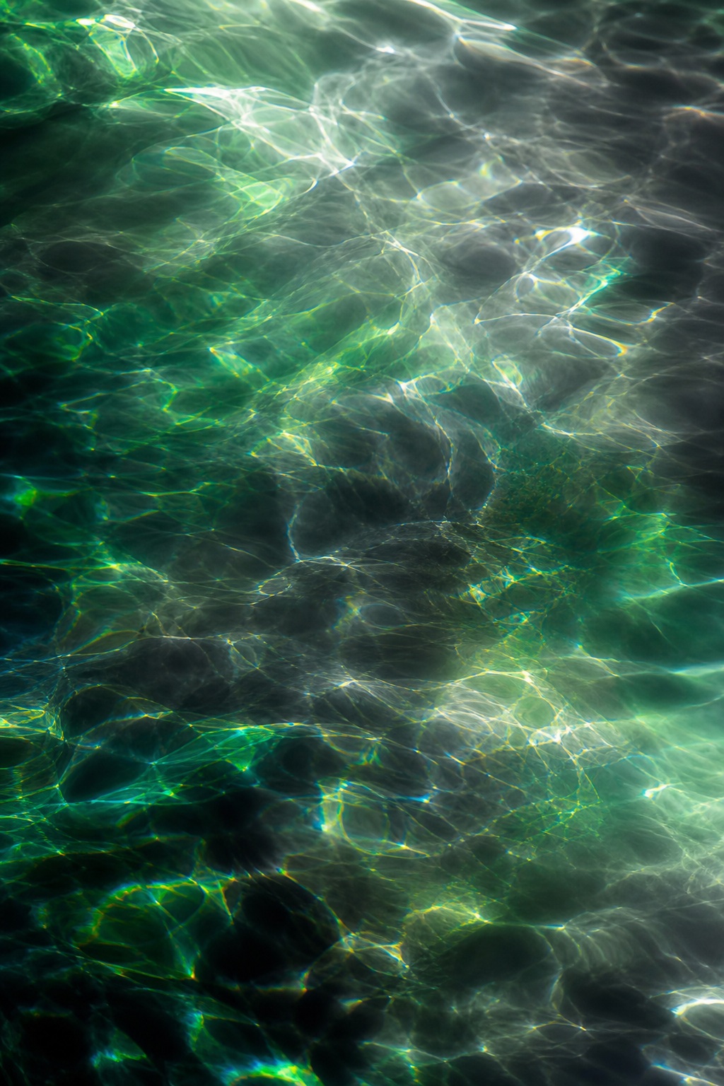 Abstract emerald and charcoal light reflections across a dark glass-like surface.