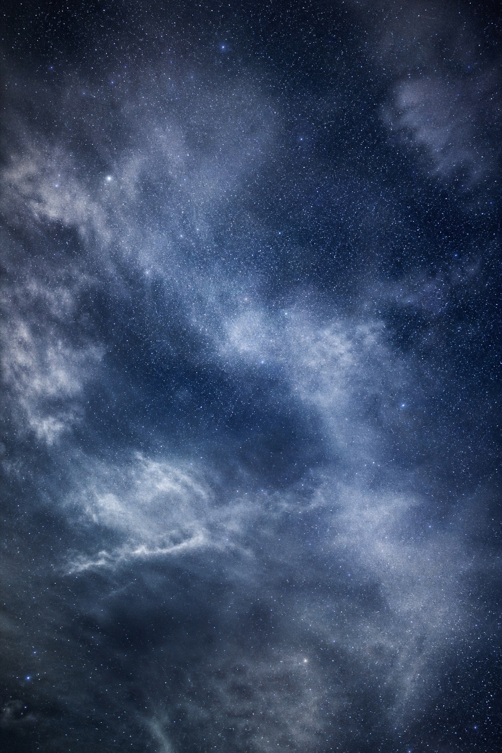 Silver blue clouded star field with wispy clouds across a dark night sky
