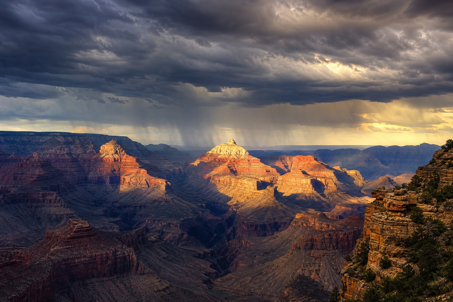 Aerial view of the Grand Canyon with dramatic clouds and warm sunlight on sandstone cliffs.