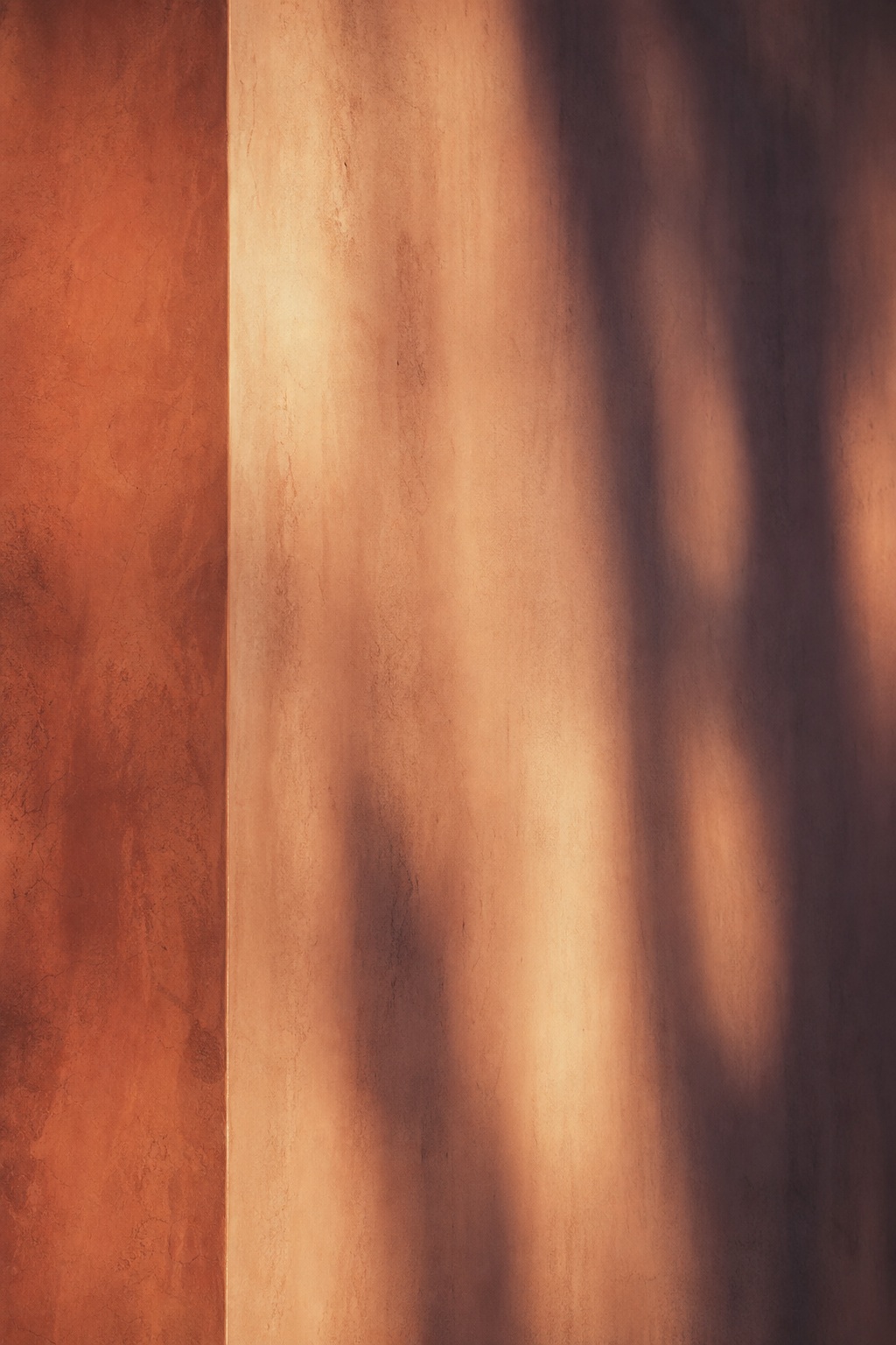 Warm orange-brown wall with soft vertical shadows drifting down the surface
