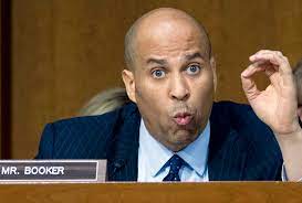 Cory Booker speaking at a congressional hearing with a nameplate in front of him.