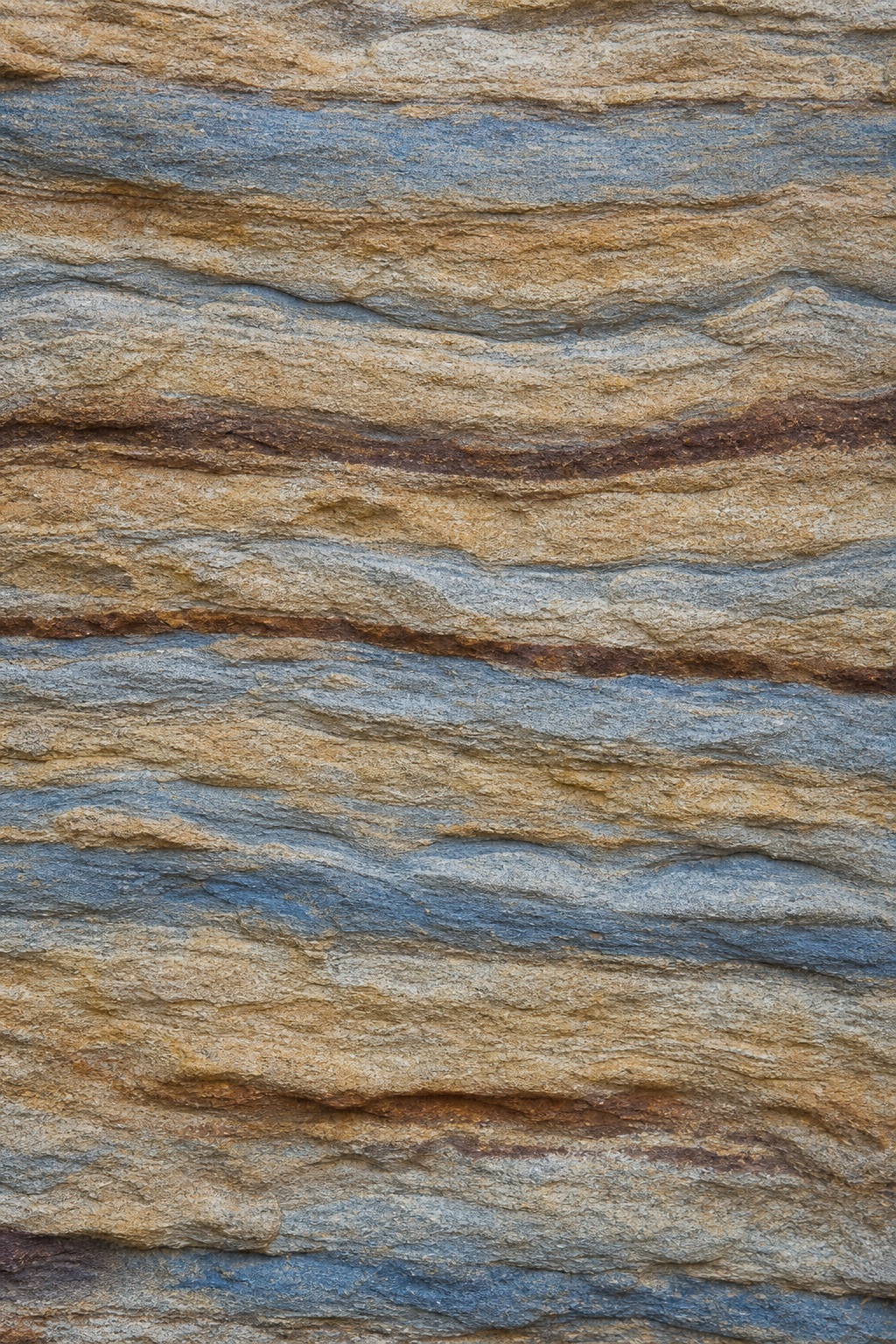 Layered sandstone texture with blue and brown iron sediment bands