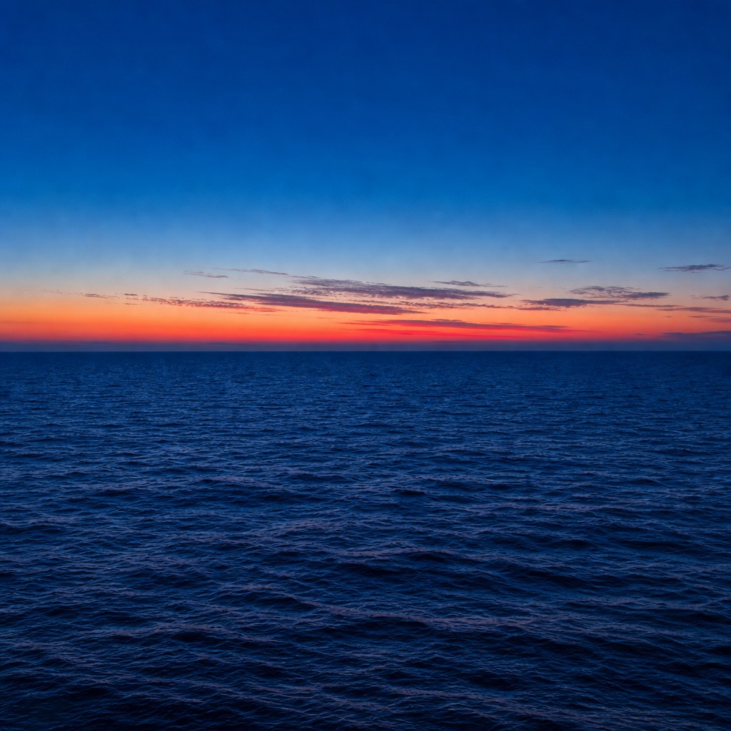 Square view of dark ocean water beneath a colorful sunset horizon