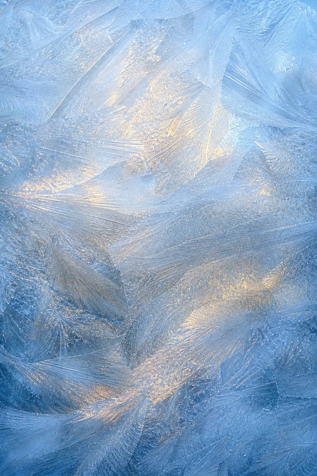 Blue frosted ice surface with layered frost patterns and warm light highlights