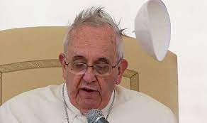 Pope Francis speaking into a microphone at a podium.