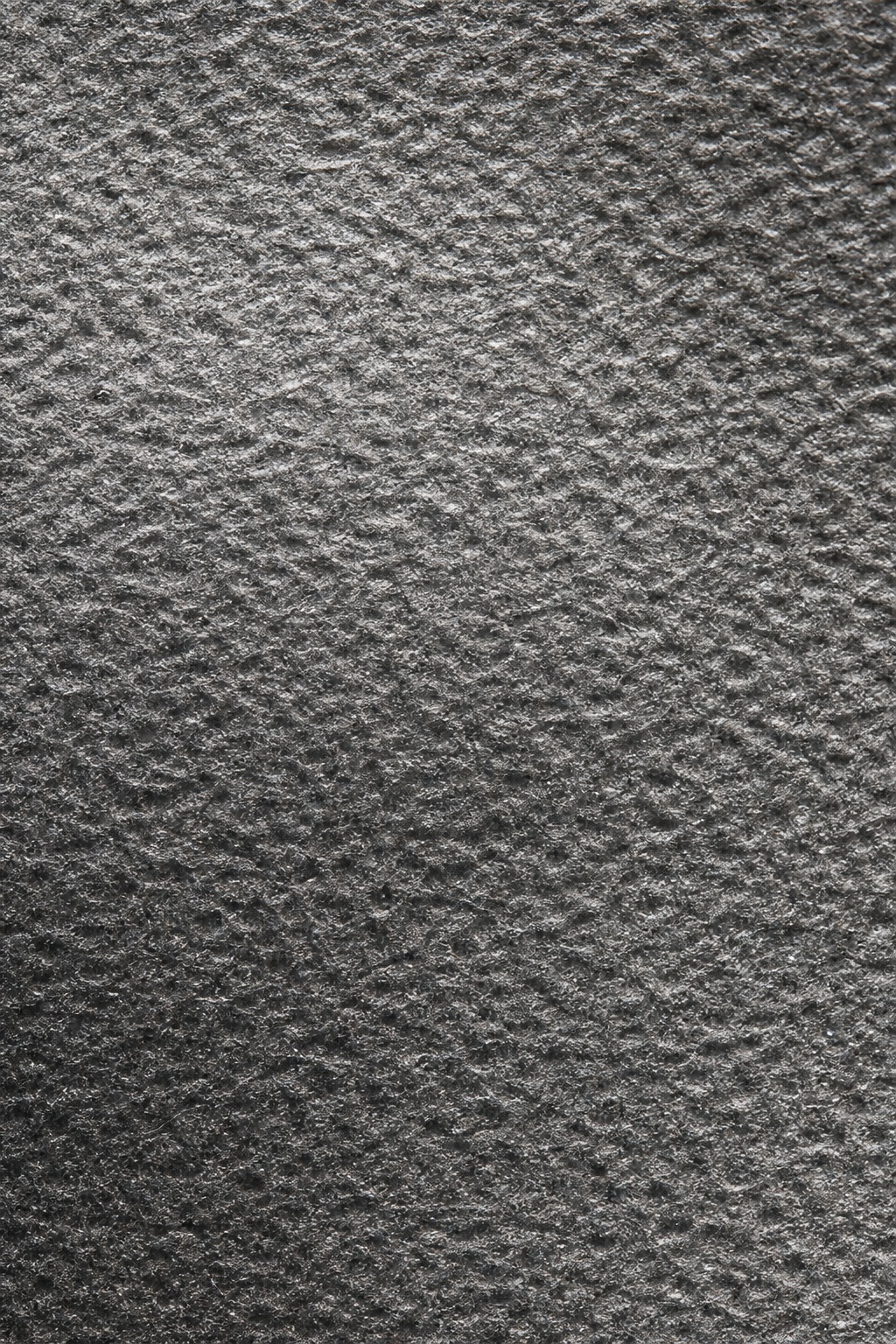 Dark charcoal textured paper surface with fine embossed stippled relief.