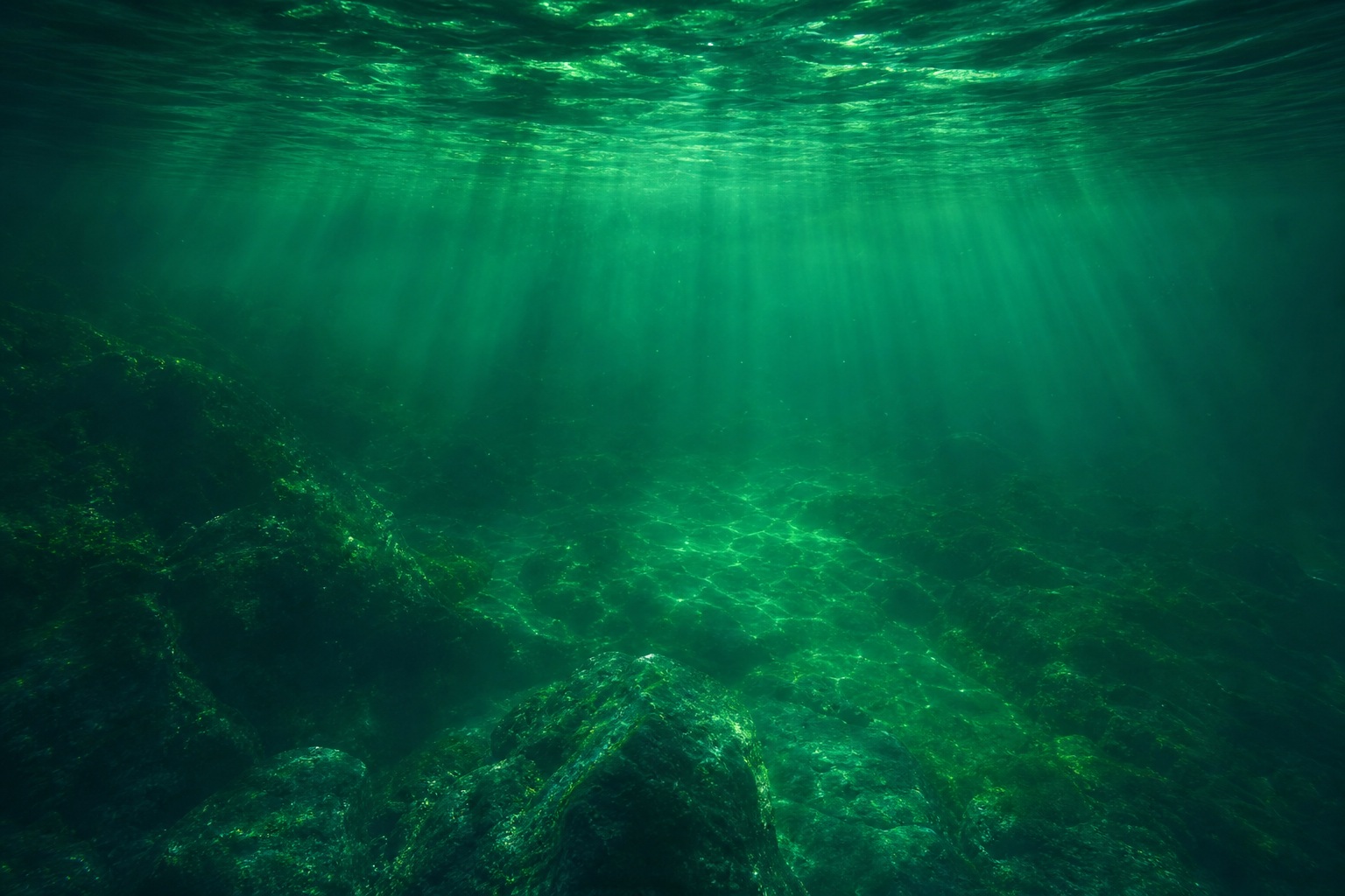 Emerald green underwater scene with light rays and hazy ocean depth