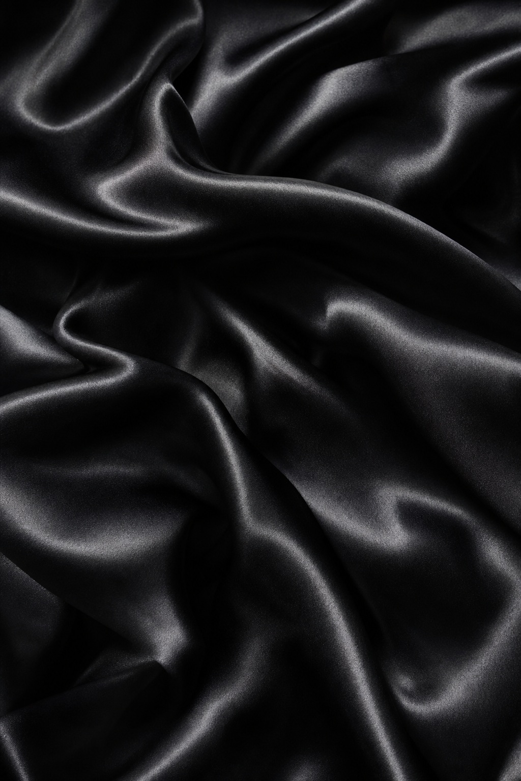 Vertical folds of shiny black silk fabric with a soft textured surface