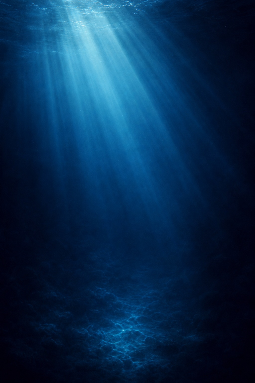 Blue underwater scene with bright light rays filtering down through deep ocean haze.