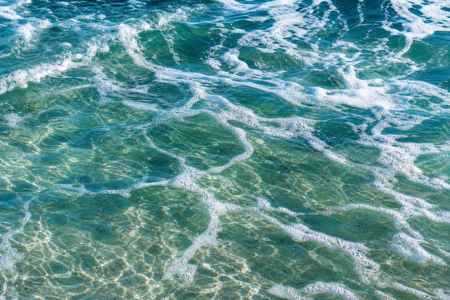 Blue ocean water with white foam patterns along the surface