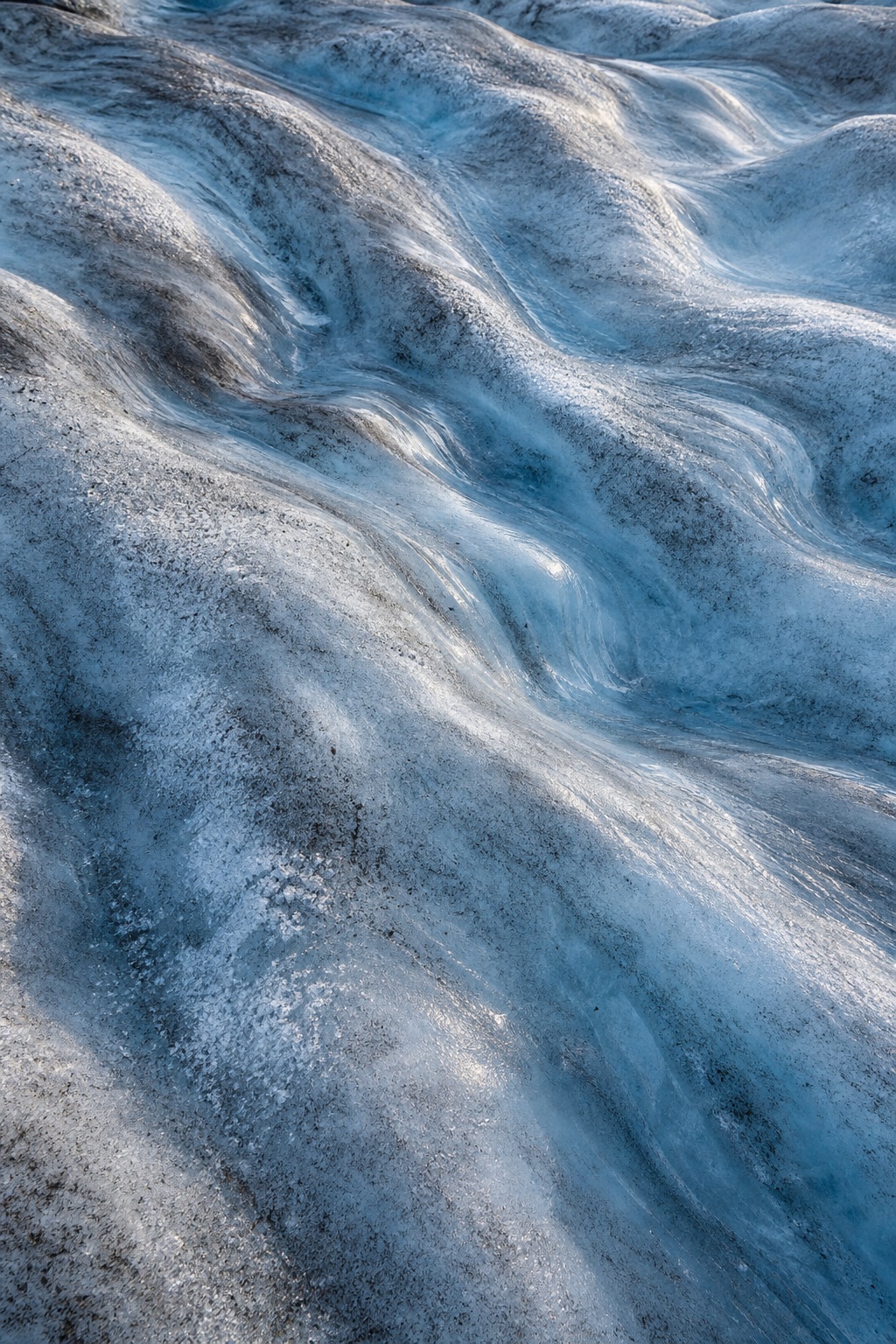 Blue glacier ice with rippled crevasses and polished melt channels