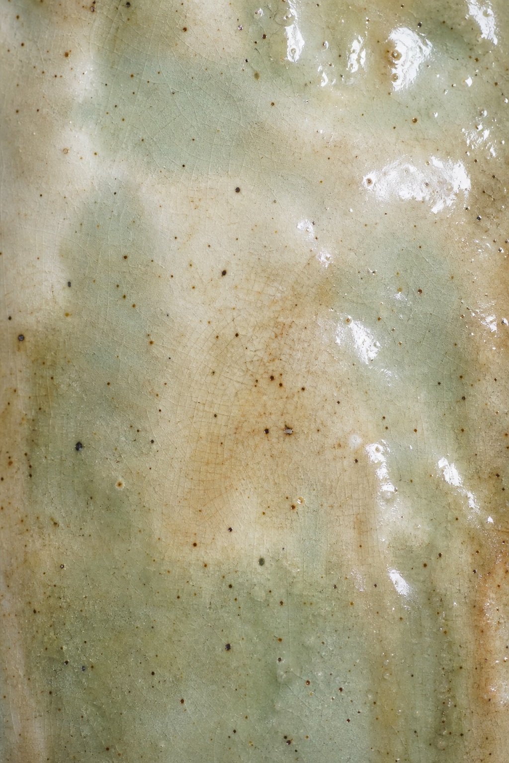 Vertical speckled ceramic glaze texture with soft green and beige tones