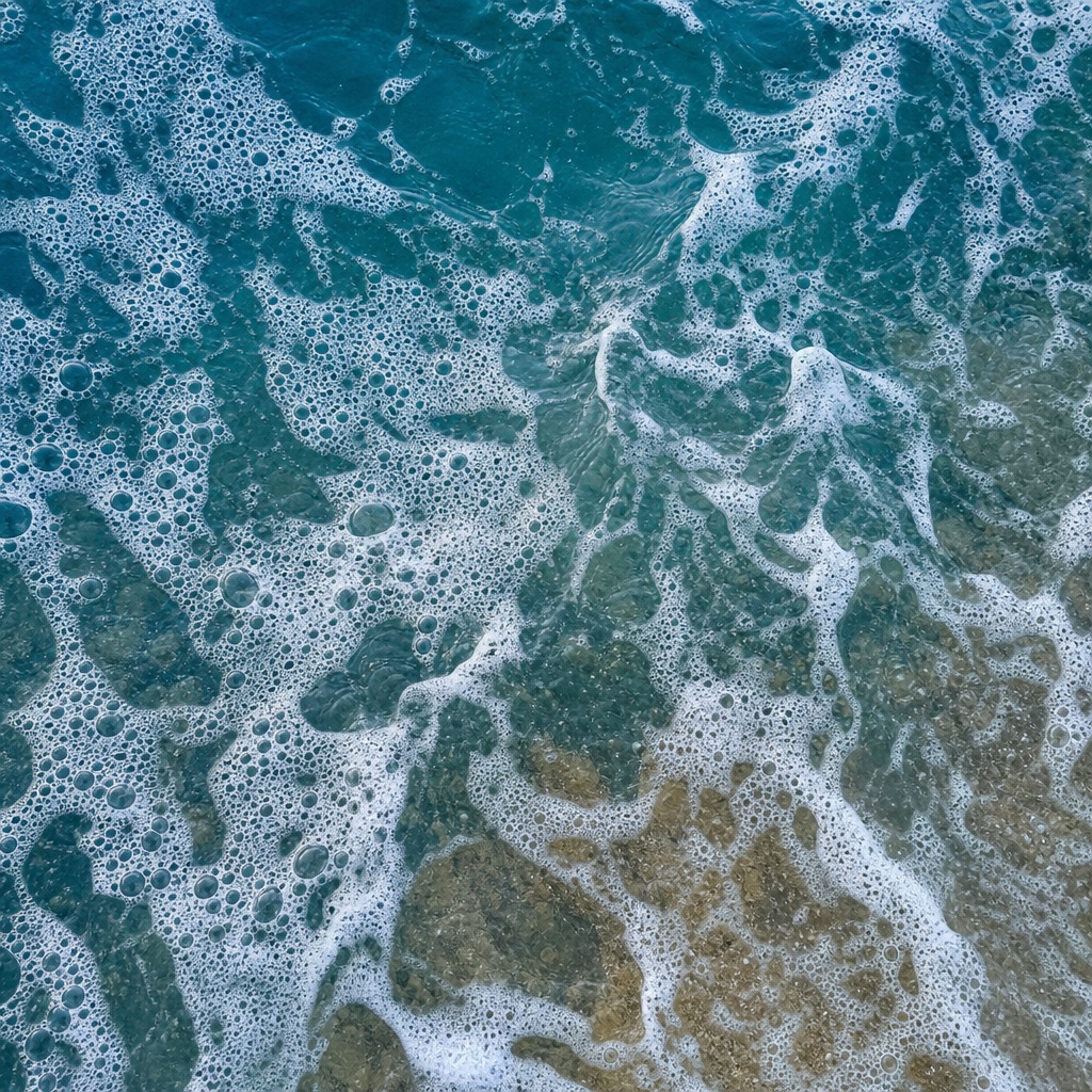 Abstract deep teal water with white sea foam and dispersed bubble patterns