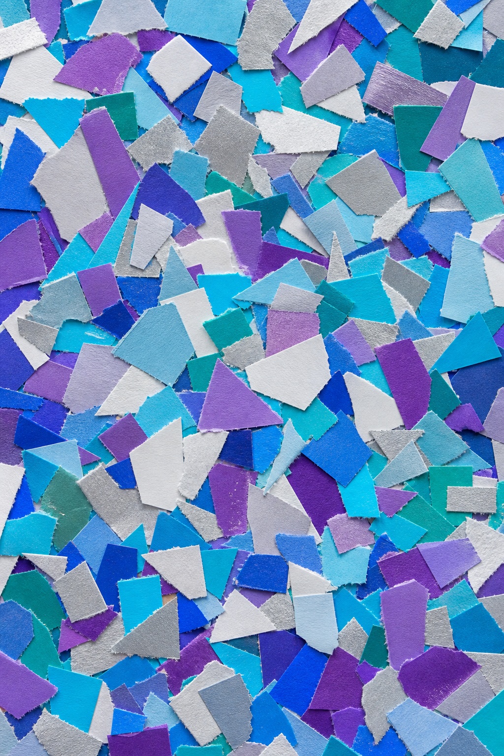 Colorful torn paper confetti pieces scattered in a dense mosaic pattern