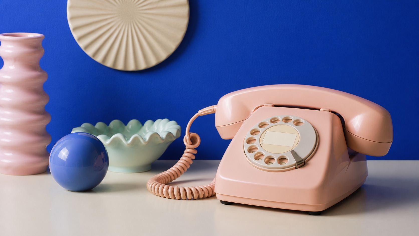 Pink rotary phone with abstract shapes on a blue retro still life background