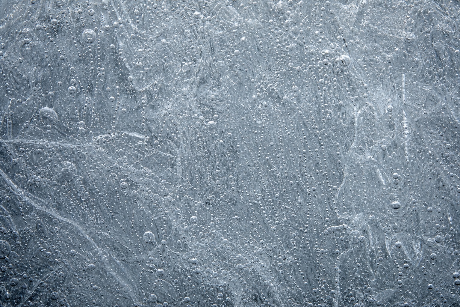 Frosted silver ice surface with trapped air layers and fine winter texture