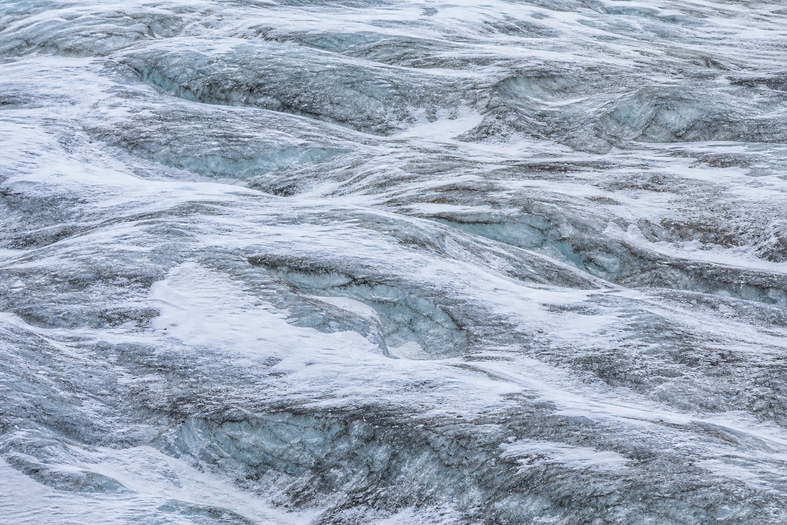 Wind scoured snow and blue glacial ice with crevasse texture