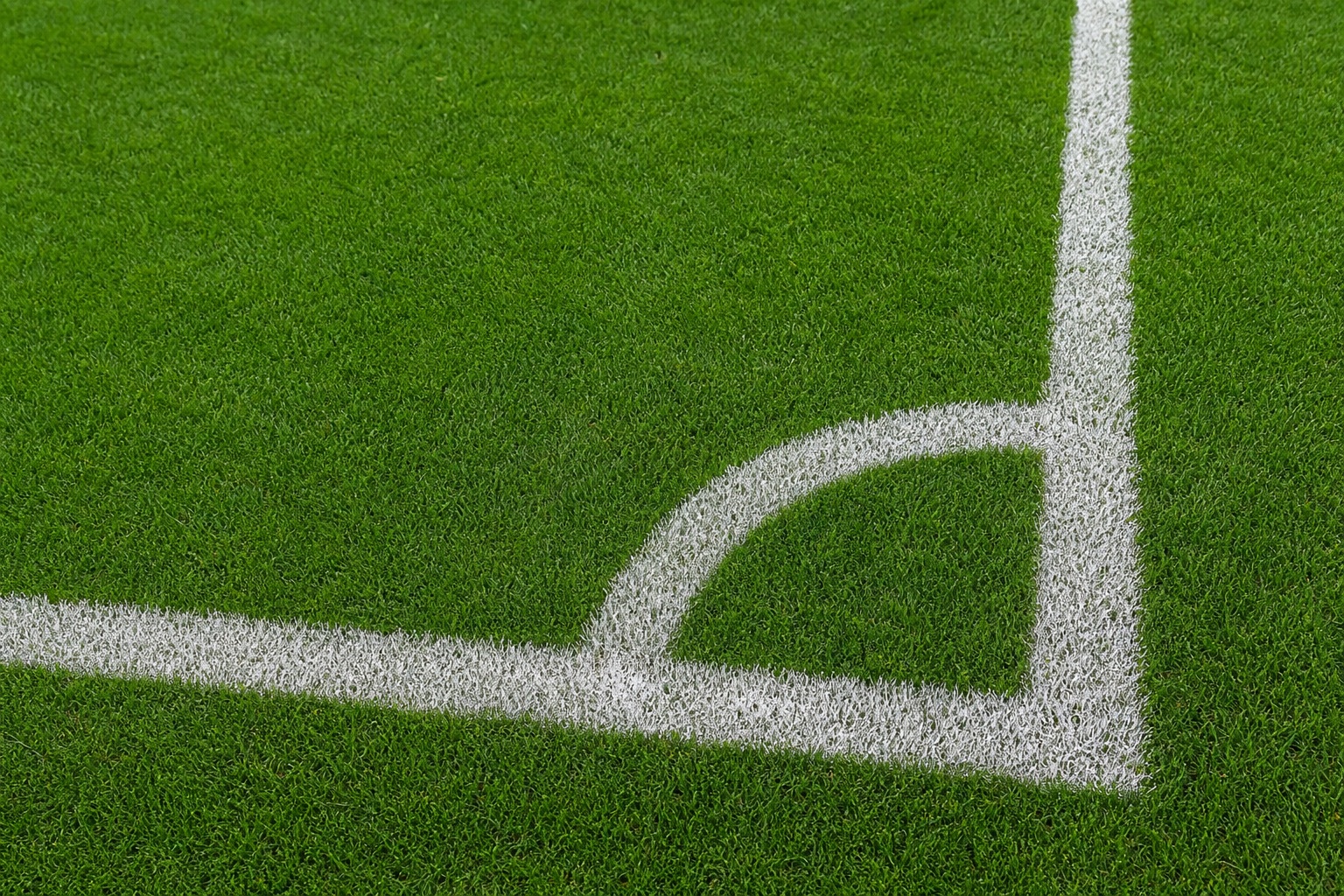 Green soccer turf with white chalk corner lines and arc marking