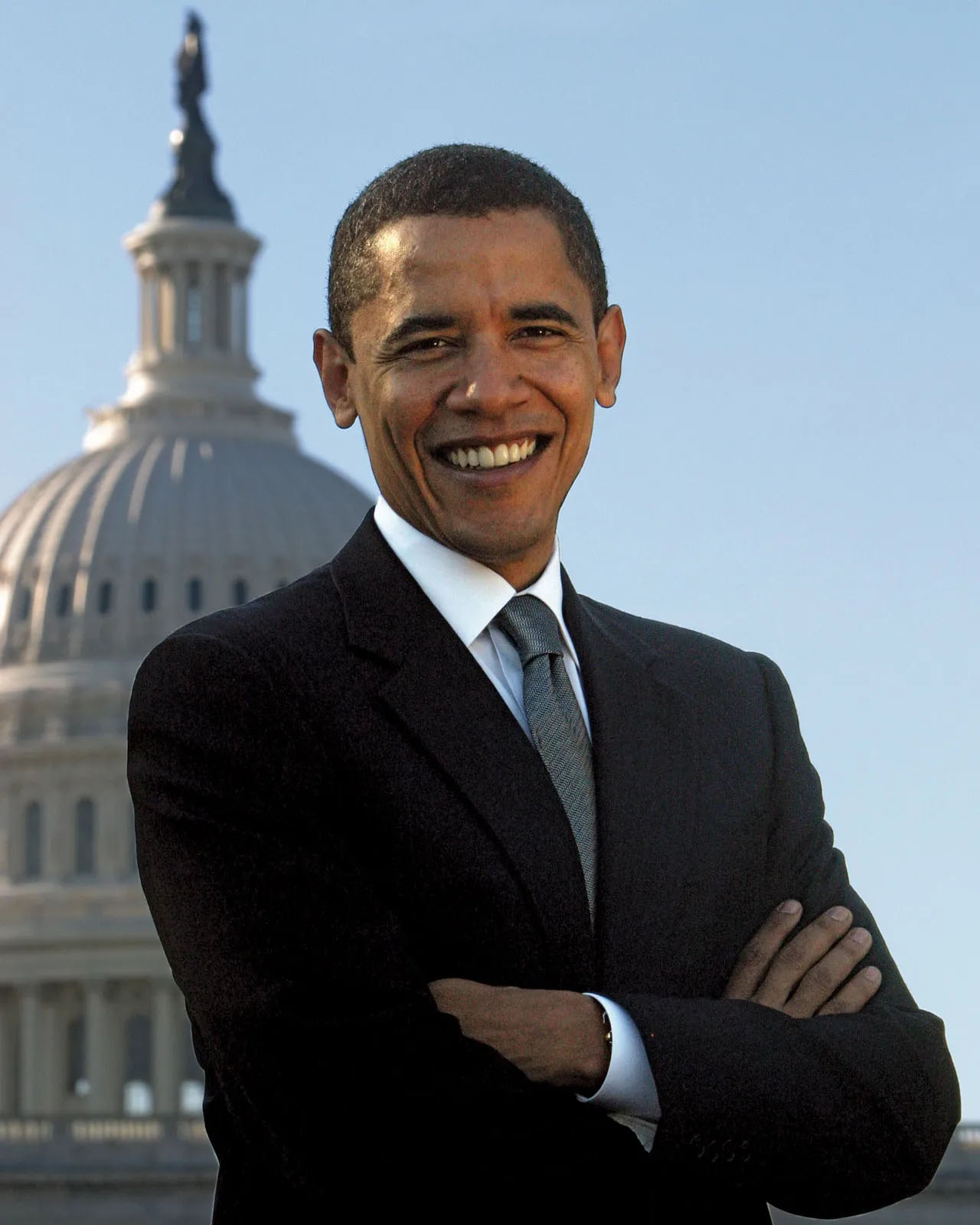 Smiling Barack Obama standing with the U.S. Capitol dome behind him.