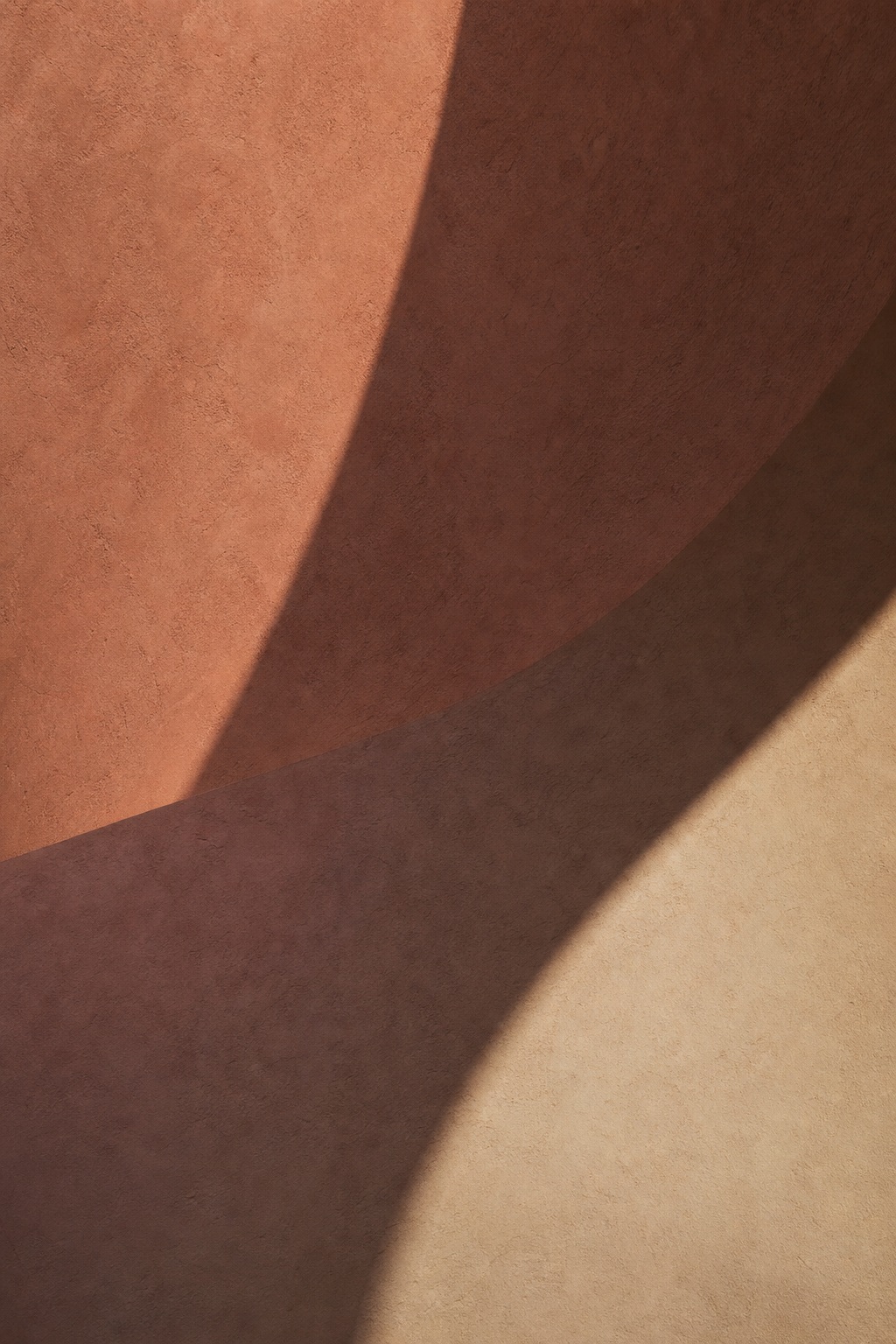 Warm curved wall with a large diagonal shadow and soft evening light.