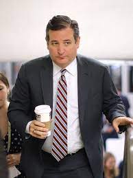 Man in a suit holding a coffee cup in a busy indoor setting