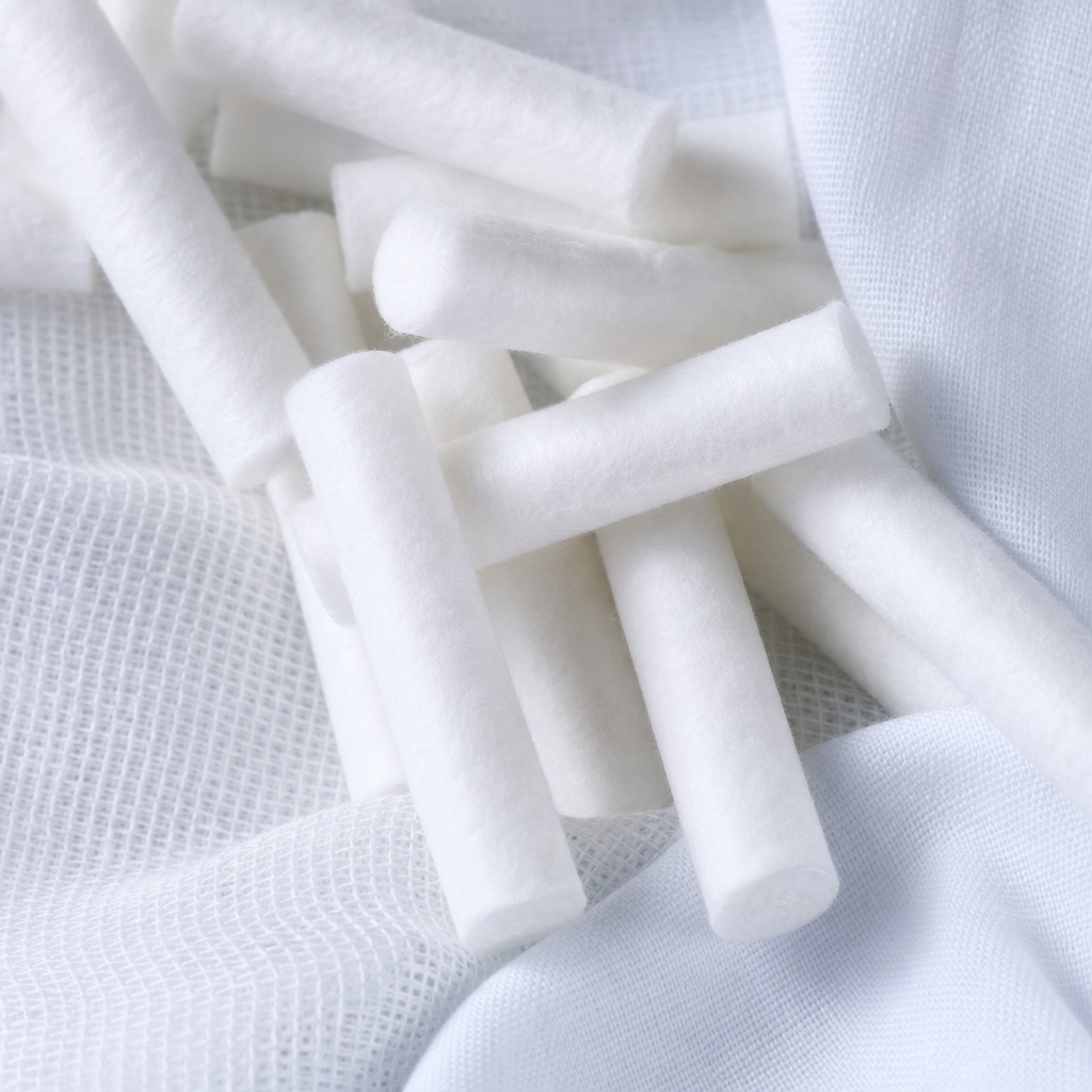 White dental cotton rolls arranged on a soft textured fabric background.