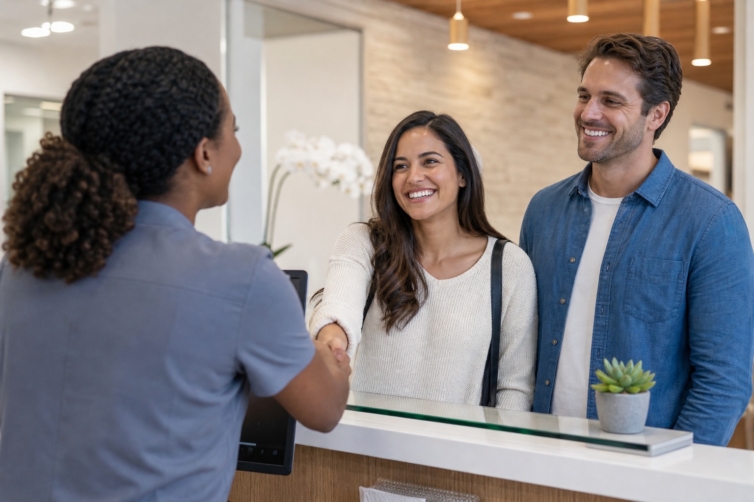 Patient speaking with two healthcare staff members at a bright reception desk