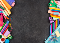 Colorful school supplies arranged in a border on a dark gray background