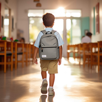 Young boy with backpack walking into a classroom