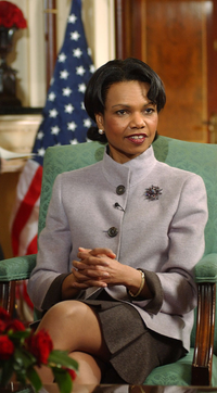 Condoleezza Rice sitting in a green chair with an American flag behind her