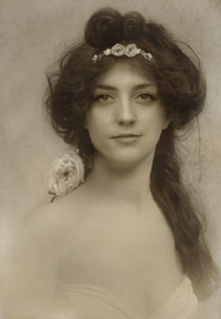 A vintage portrait of a woman with a floral headband and elegant attire