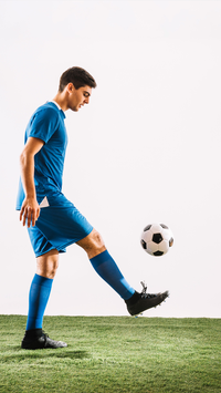 A man in blue soccer uniform kicking a soccer ball