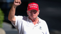 Donald Trump in a red Make America Great Again hat and white polo shirt