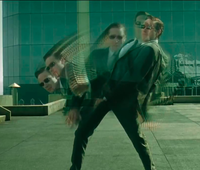 Two individuals in black attire and sunglasses posing dynamically in a modern setting