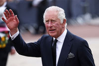 King Charles III waving in a formal black suit