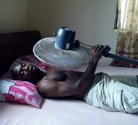 Man lying on a bed with a fan on his head