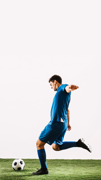 Soccer player in blue kicking a ball