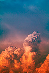 A volcanic eruption illuminating clouds with vibrant orange against a blue sky