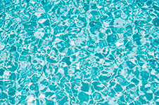 Clear blue pool water with sunlight reflections on the surface.