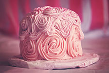 Pink cake with intricate rose designs on a marble plate