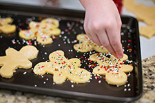 Hand decorating gingerbread cookies with sprinkles