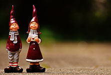 Two garden gnomes, a male and female, standing side by side on a dirt path