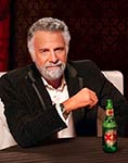 The Most Interesting Man in the World sitting with a green beer bottle