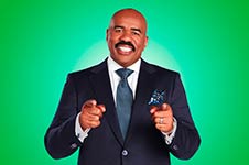Steve Harvey in a suit pointing at the viewer