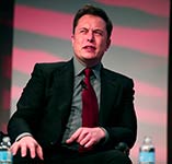 Elon Musk sitting on a stage